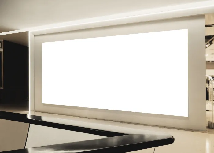 Gran rótulo rectangular blanco en blanco expuesto en una pared interior sobre un mostrador blanco y negro brillante en un espacio moderno y bien iluminado.